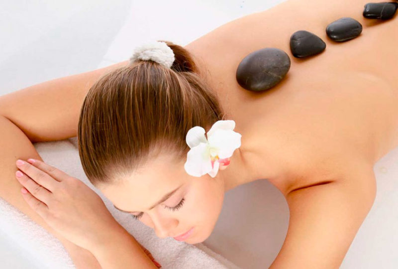 How is a hot stone massage performed?